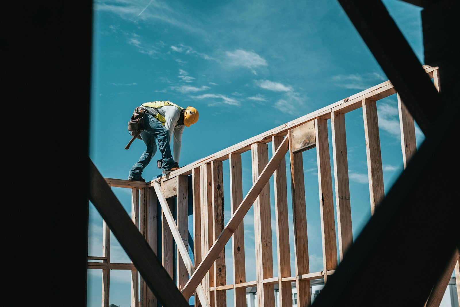 A construction worker in a hard hat framing a house