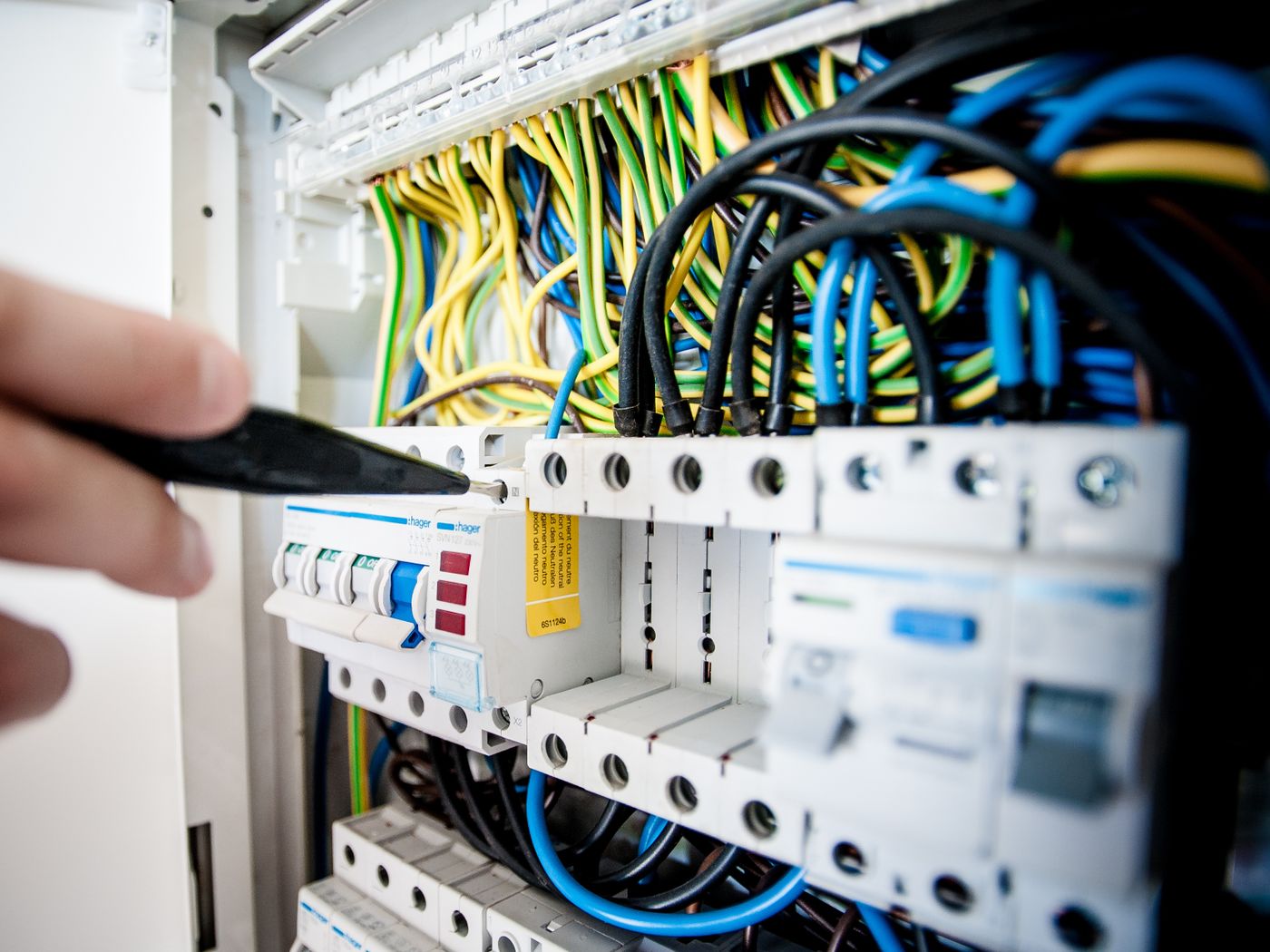 An electrician working inside an open panel